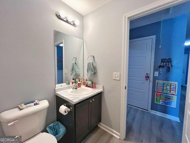 half bath with wood finished floors, vanity, toilet, and baseboards