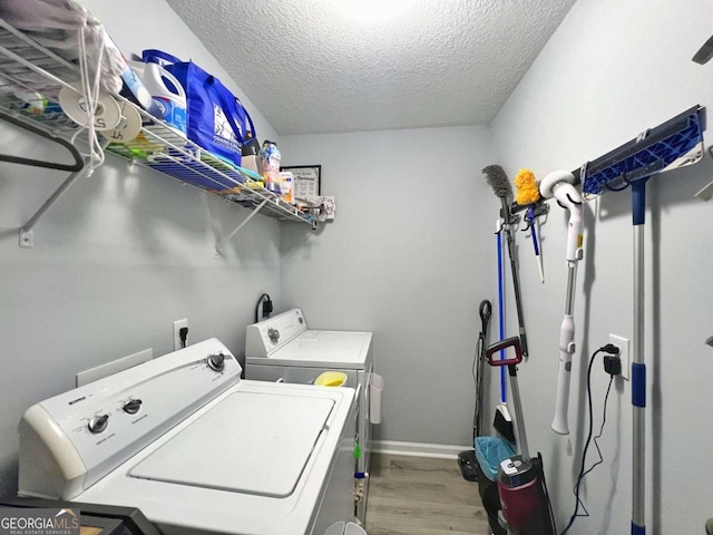 laundry area with wood finished floors, separate washer and dryer, a textured ceiling, and baseboards