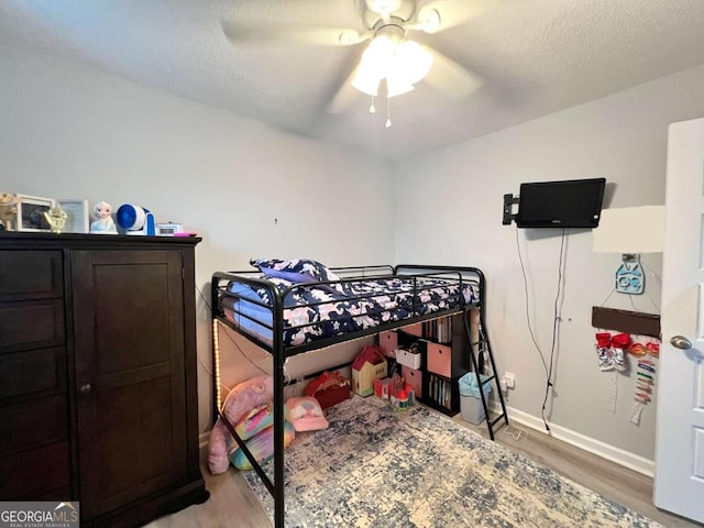 bedroom with light wood-style flooring, baseboards, a ceiling fan, and a textured ceiling