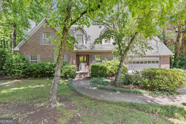 cape cod home with brick siding, an attached garage, a front yard, and a shingled roof