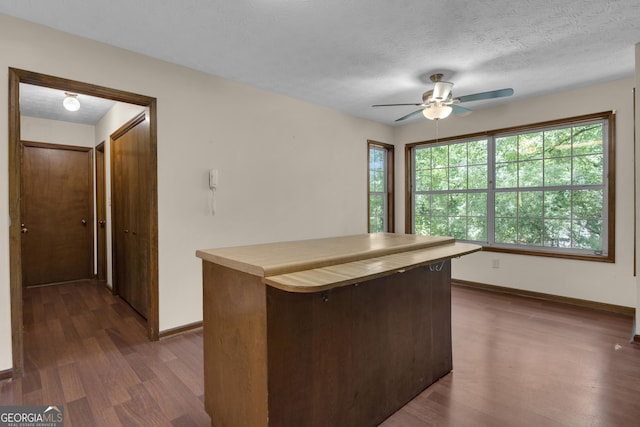 kitchen featuring ceiling fan, dark wood-style floors, baseboards, plenty of natural light, and a textured ceiling