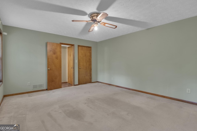 unfurnished bedroom with baseboards, carpet, a textured ceiling, and a ceiling fan