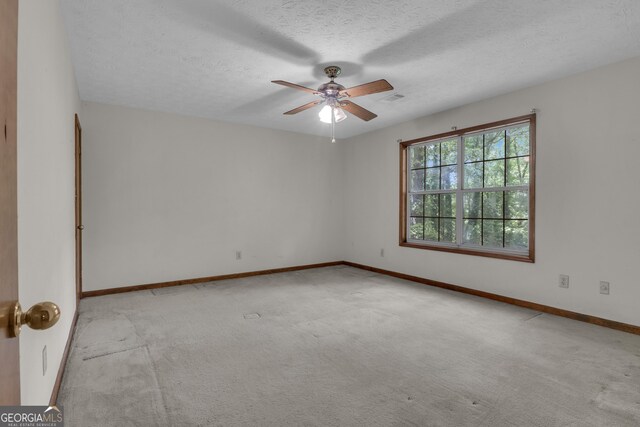 carpeted empty room featuring a ceiling fan, a textured ceiling, and baseboards