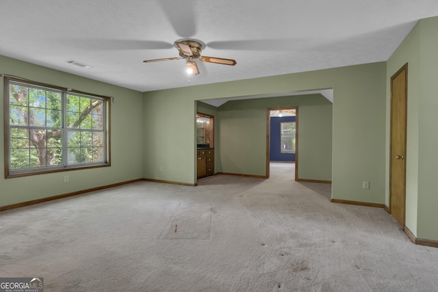 unfurnished room featuring ceiling fan, light carpet, and baseboards