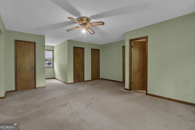 unfurnished bedroom featuring multiple closets, baseboards, carpet, and ceiling fan