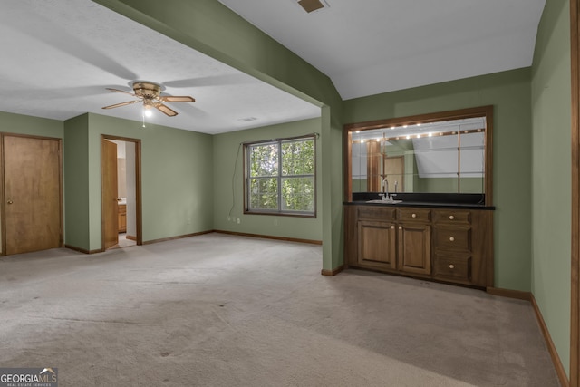 unfurnished living room with light carpet, baseboards, a sink, and ceiling fan
