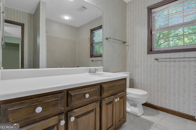 bathroom featuring plenty of natural light, tile patterned flooring, toilet, vanity, and wallpapered walls
