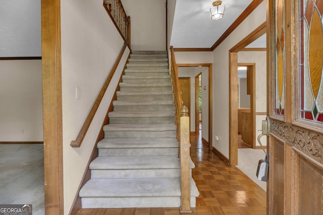staircase with baseboards and crown molding