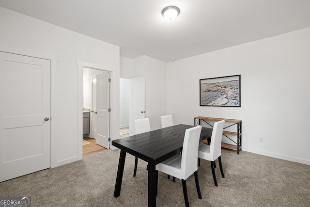 dining space featuring light colored carpet and baseboards
