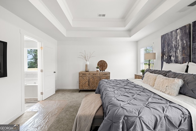 carpeted bedroom featuring a raised ceiling, ornamental molding, ensuite bathroom, and baseboards