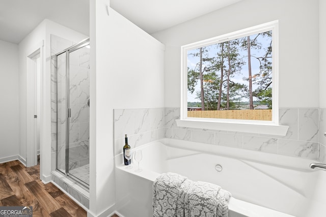 bathroom with a shower stall, a bath, and wood finished floors
