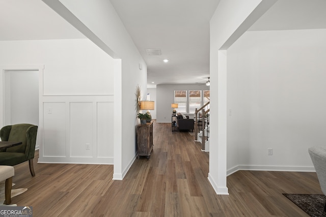 sitting room with wood finished floors, a ceiling fan, recessed lighting, stairs, and a decorative wall