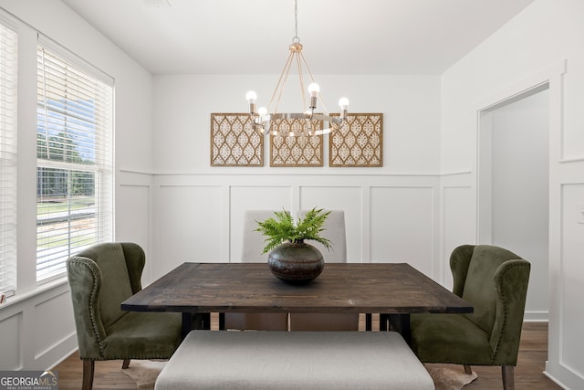 dining space with a decorative wall, a chandelier, wood finished floors, and a wainscoted wall