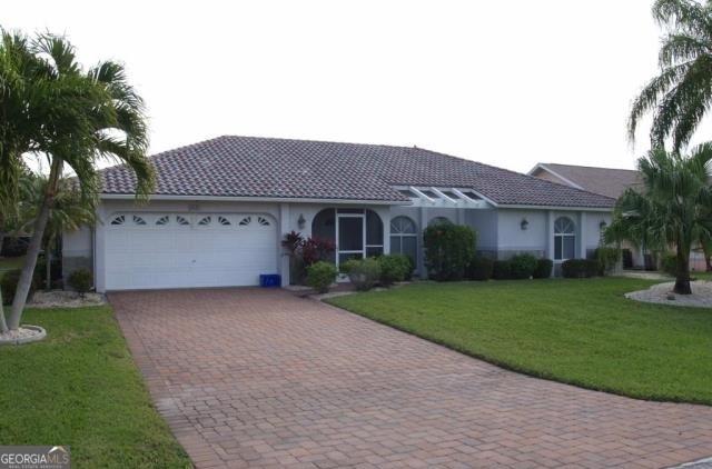 ranch-style house with an attached garage, decorative driveway, a front yard, and stucco siding