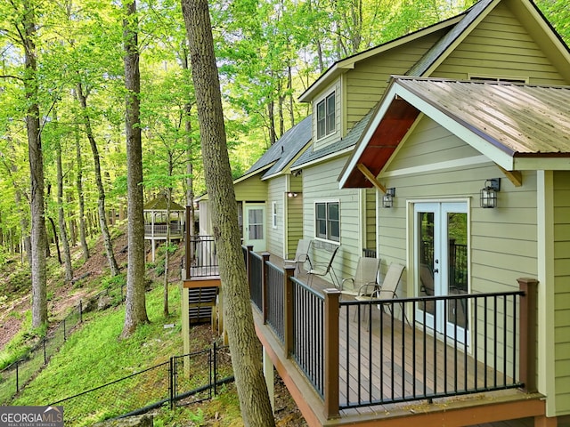 back of house with a deck, fence, french doors, and metal roof