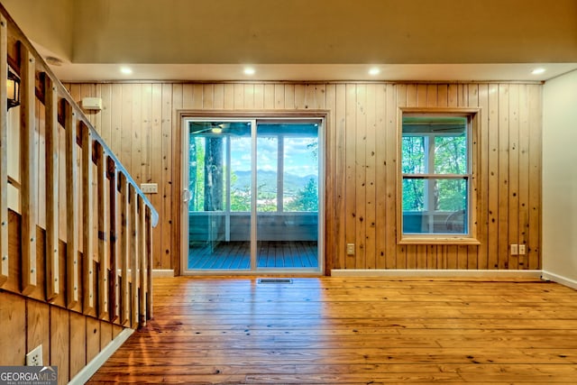 doorway to outside featuring hardwood / wood-style flooring, recessed lighting, wooden walls, and stairs