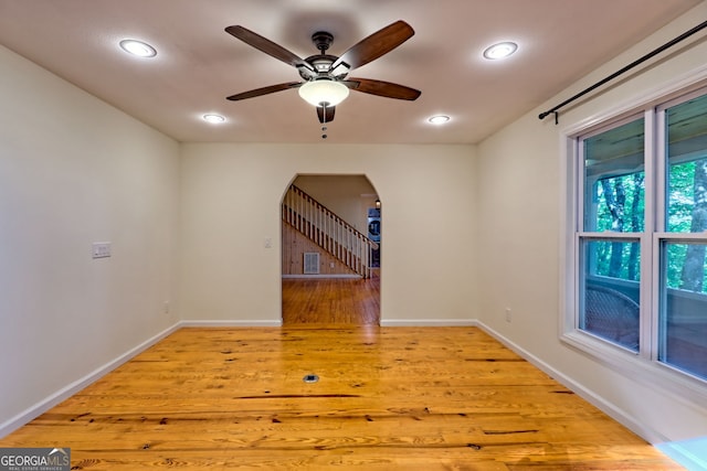 empty room with arched walkways, wood finished floors, recessed lighting, ceiling fan, and baseboards