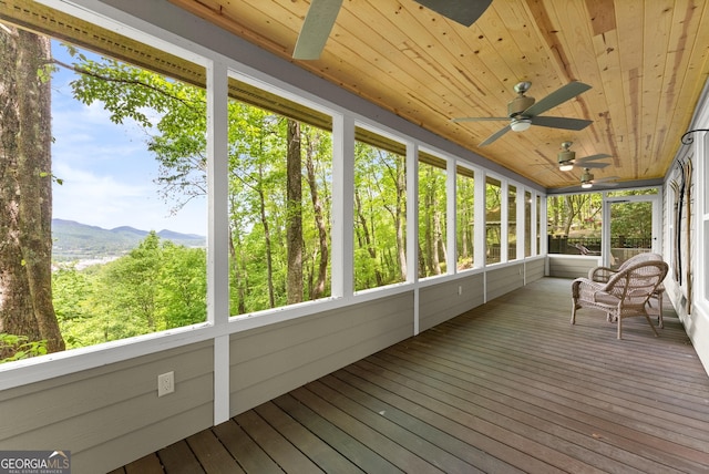sunroom with ceiling fan and a mountain view
