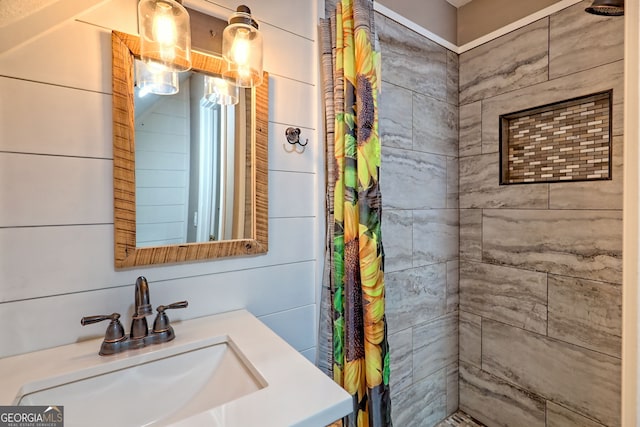 bathroom with a tile shower and vanity