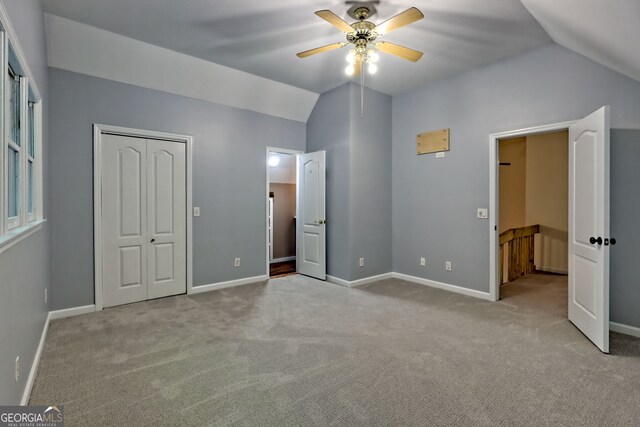 unfurnished bedroom featuring lofted ceiling, carpet, baseboards, and a ceiling fan