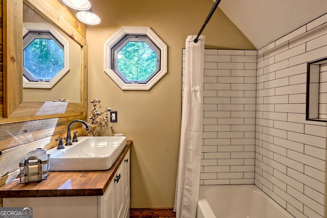 full bathroom featuring vanity, lofted ceiling, and shower / bathtub combination with curtain