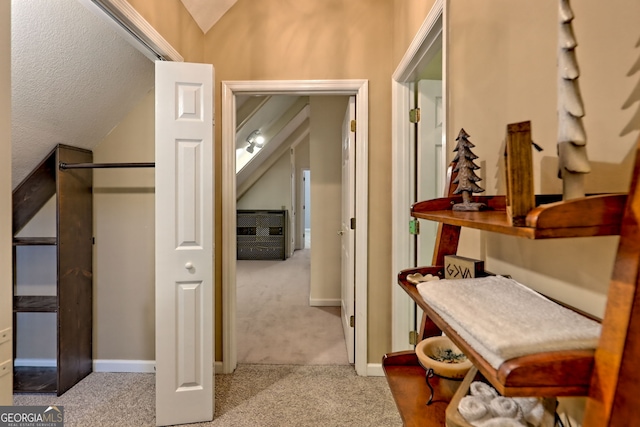 hall with carpet flooring, vaulted ceiling, and baseboards