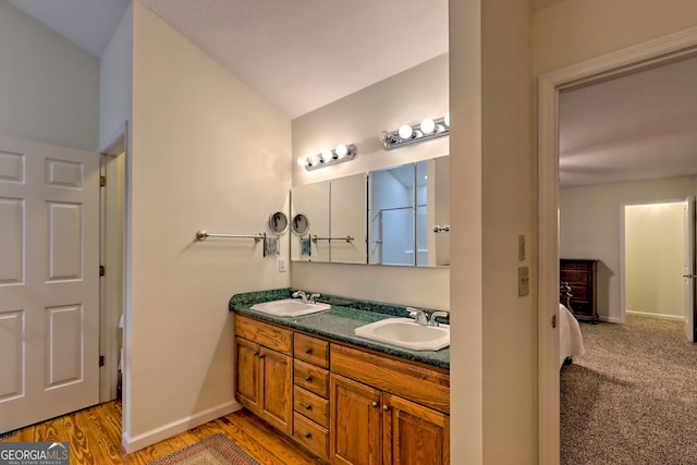 full bathroom featuring double vanity, baseboards, and wood finished floors