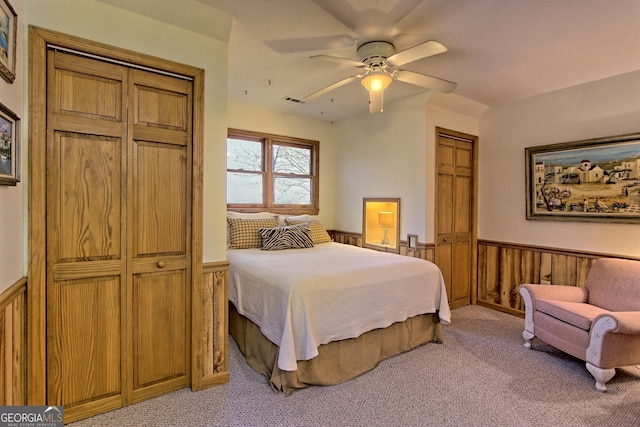 bedroom with a wainscoted wall, light carpet, and a ceiling fan