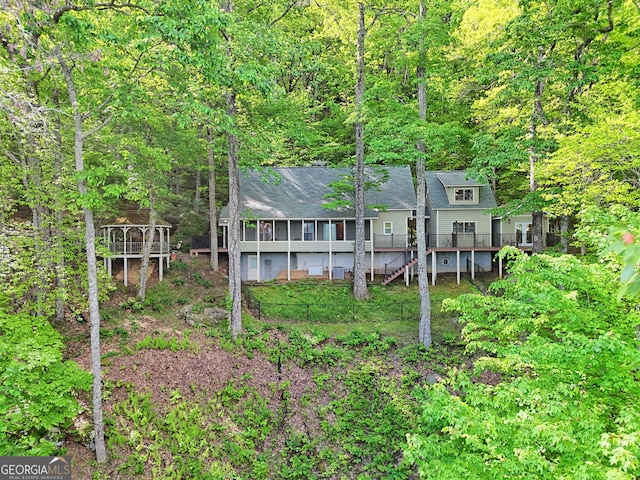 rear view of property featuring a wooded view and a wooden deck