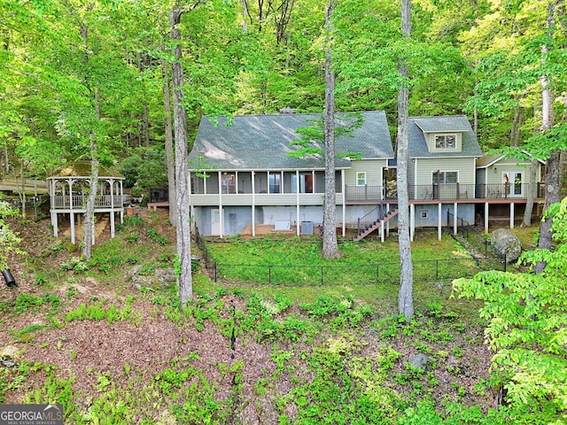 rear view of house with fence, a wooden deck, and roof with shingles