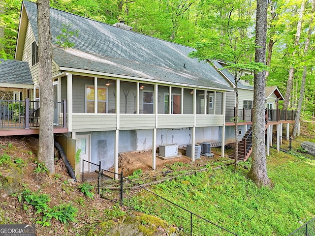 rear view of property with a sunroom, a shingled roof, a wooden deck, stairs, and central air condition unit