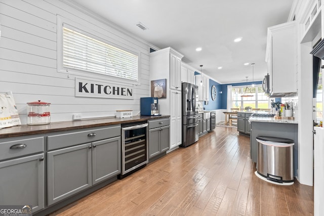 58 Gables Way, Newnan, GA 30265 - kitchen featuring gray cabinetry, wine cooler, stainless steel appliances, light wood-style flooring, and pendant lighting