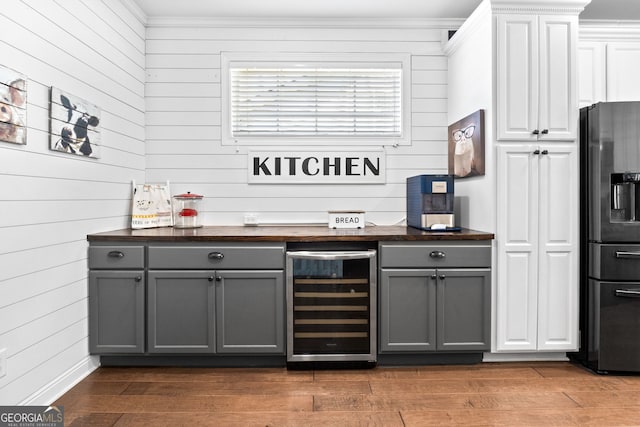58 Gables Way, Newnan, GA 30265 - indoor dry bar with wine cooler, fridge with ice dispenser, wood finished floors, ornamental molding, and wood walls