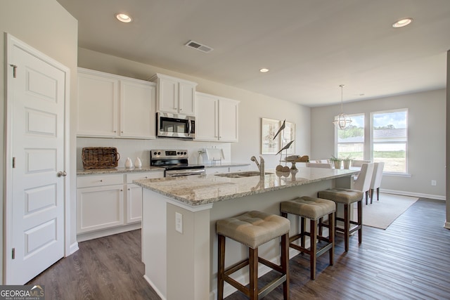 kitchen with stainless steel appliances, a sink, a kitchen breakfast bar, dark wood-style floors, and a kitchen island with sink