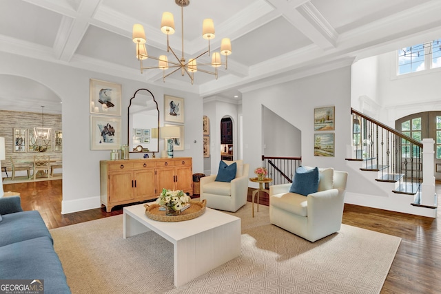 living room featuring a chandelier, arched walkways, coffered ceiling, beamed ceiling, and wood finished floors