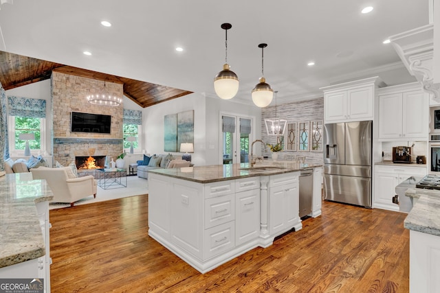kitchen with stainless steel appliances, a sink, a fireplace, recessed lighting, and white cabinets