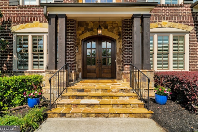 property entrance with french doors, brick siding, and stone siding