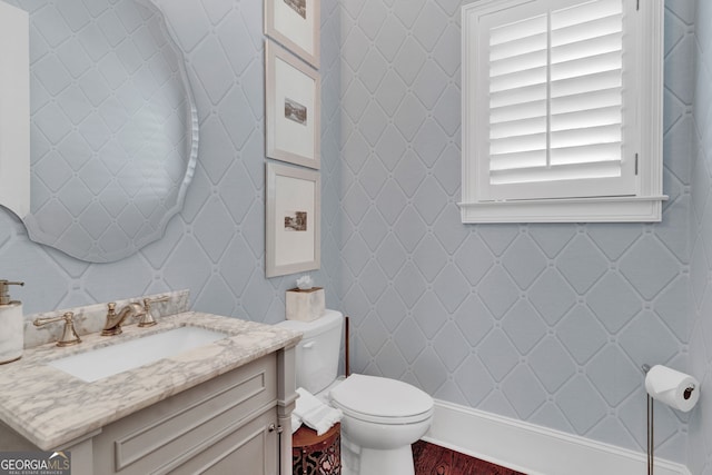 bathroom featuring wood finished floors, toilet, vanity, and baseboards