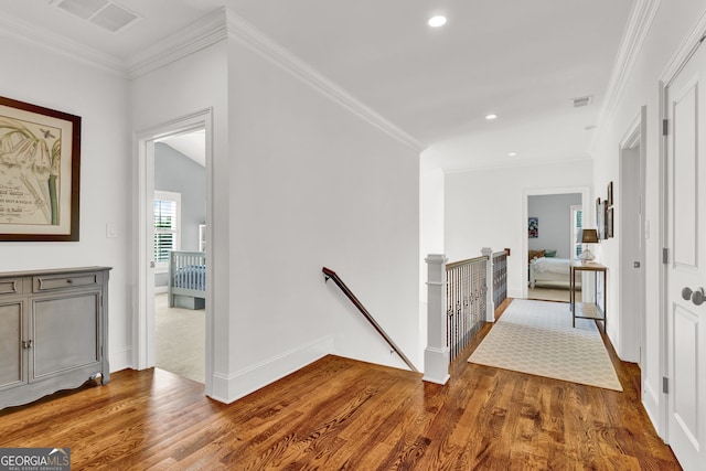 hallway with an upstairs landing, wood finished floors, baseboards, recessed lighting, and ornamental molding
