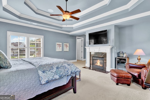 bedroom with a raised ceiling, crown molding, carpet, a fireplace, and a ceiling fan