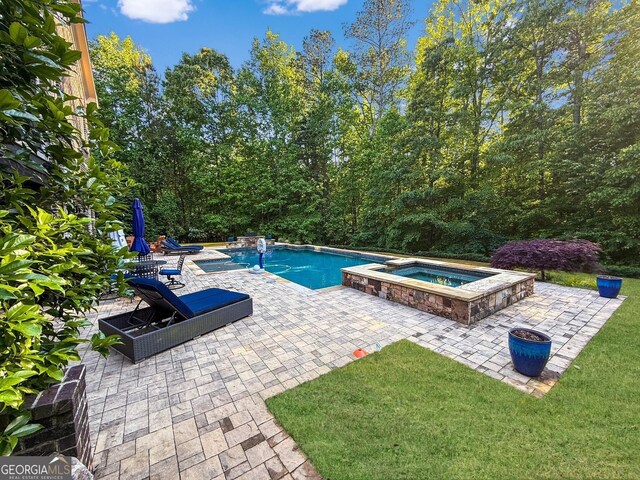 swimming pool featuring an in-ground hot tub, a patio area, and a lawn
