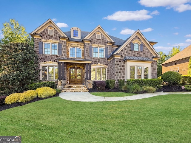 view of front of property with french doors, brick siding, a front yard, and a standing seam roof