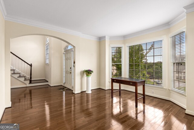 entryway featuring arched walkways, crown molding, wood finished floors, and baseboards