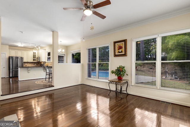 unfurnished living room featuring crown molding, a ceiling fan, dark wood finished floors, and baseboards