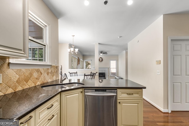 kitchen featuring stainless steel dishwasher, cream cabinetry, a sink, and backsplash