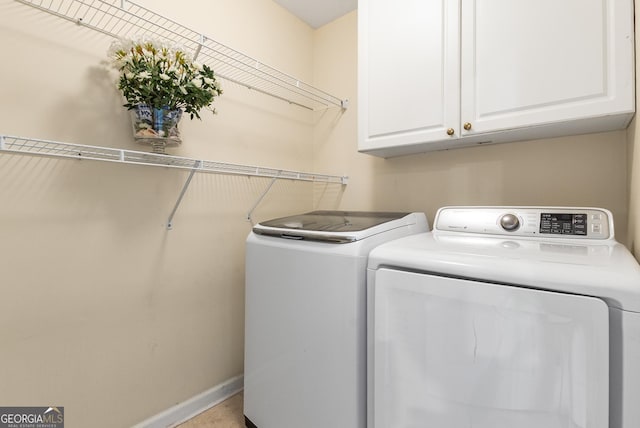 laundry area featuring separate washer and dryer, cabinet space, and baseboards