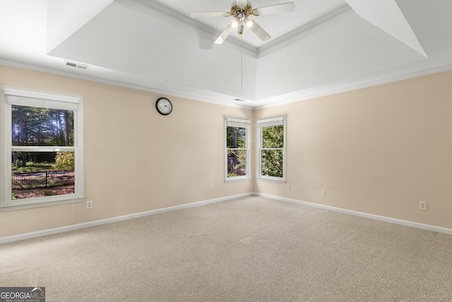unfurnished room with carpet flooring, a ceiling fan, baseboards, a tray ceiling, and crown molding