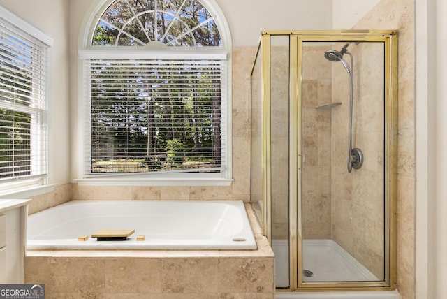 full bathroom with a shower stall, a bath, and vanity