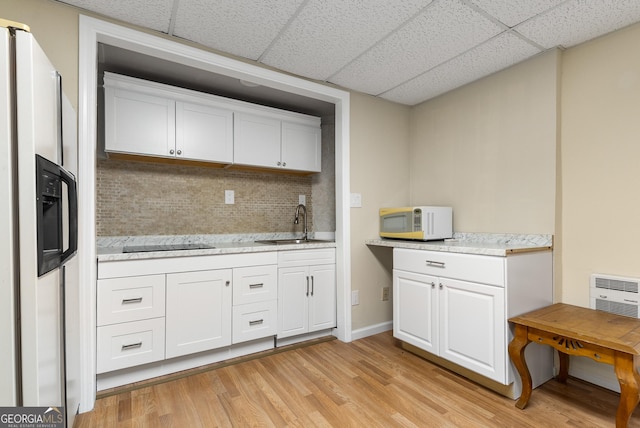 kitchen featuring white appliances, a paneled ceiling, a sink, white cabinets, and light wood finished floors