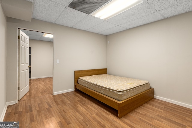 bedroom with a paneled ceiling, wood finished floors, and baseboards
